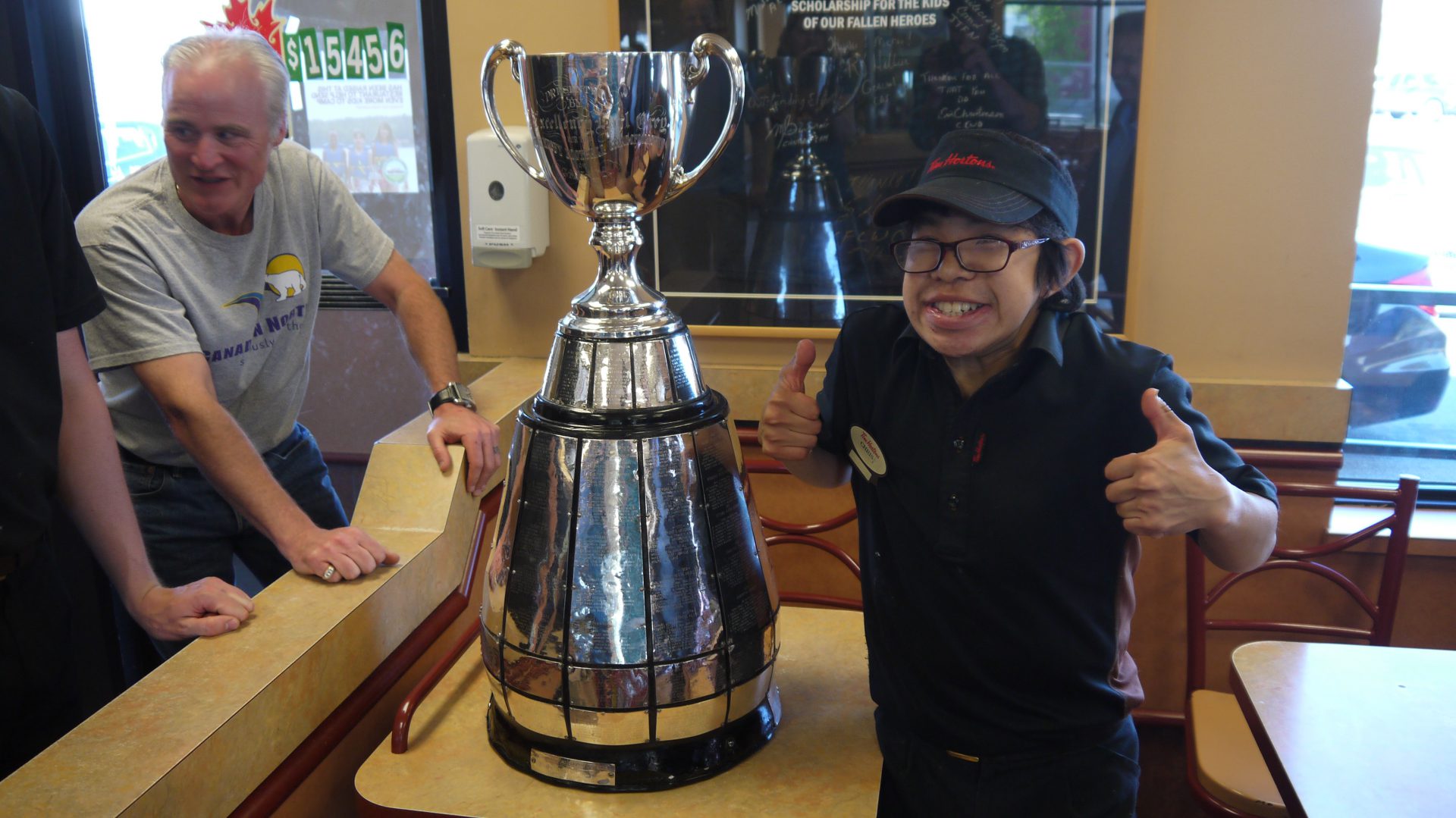 A Tim Hortons employee takes a short break to pose with the Grey Cup.