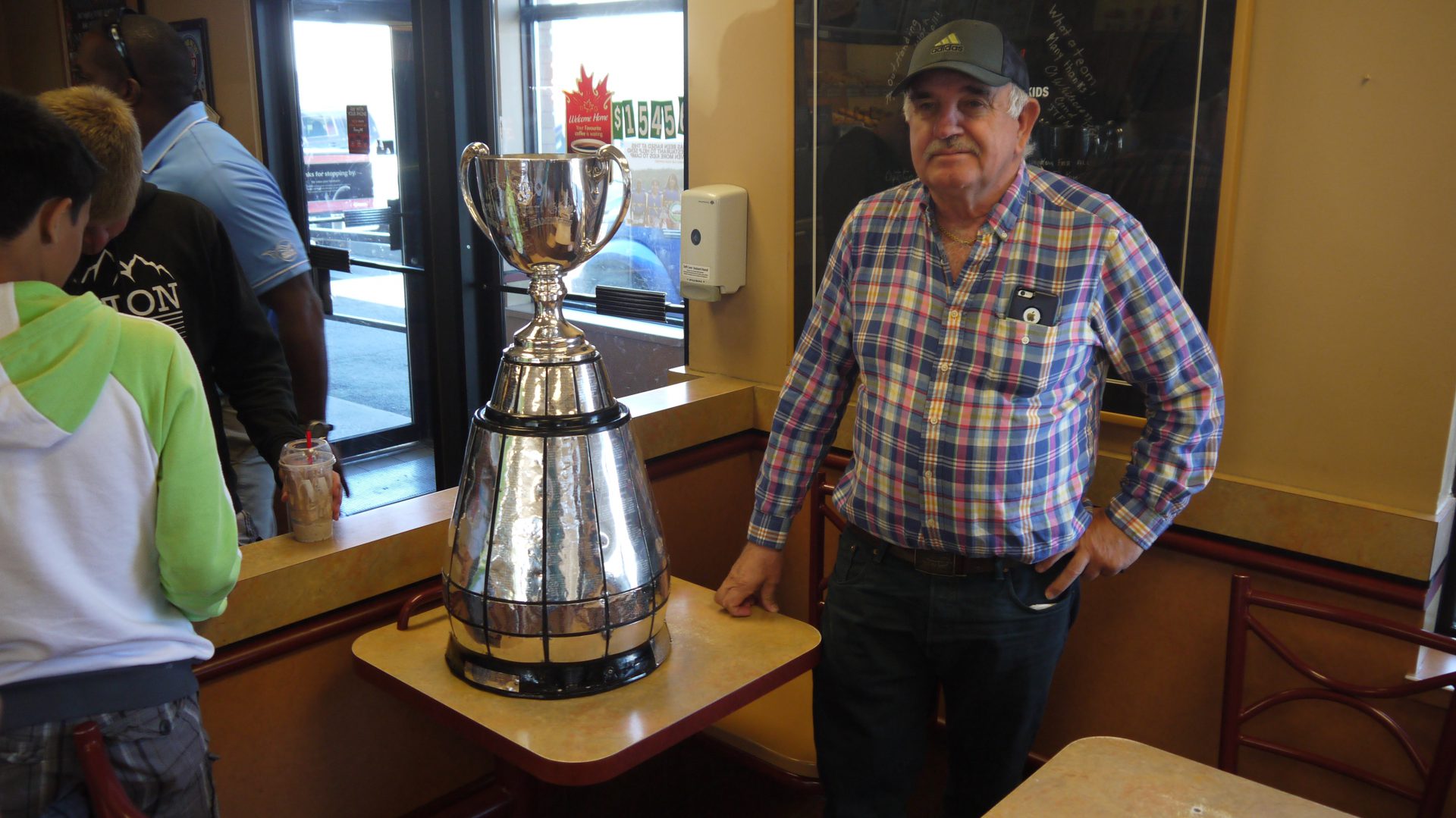 A fan poses with the Grey Cup at Tim Hortons.