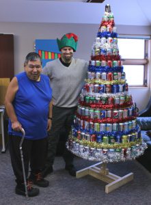 Terry Kuliktana, left, and Daron Letts stand beside the seven-foot tall Christmas tree. The tree is made out of 259 recycled pop cans.